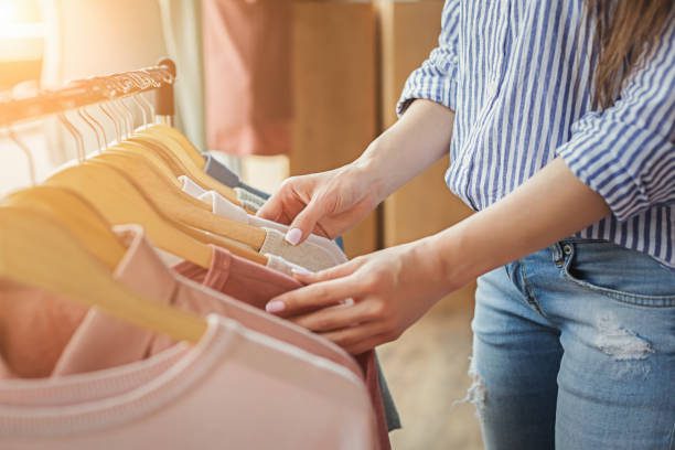 fast fashion. An unrecognizable woman chooses clothes on a rack in the showroom. Sale, fashion, and consumerism concept, crop